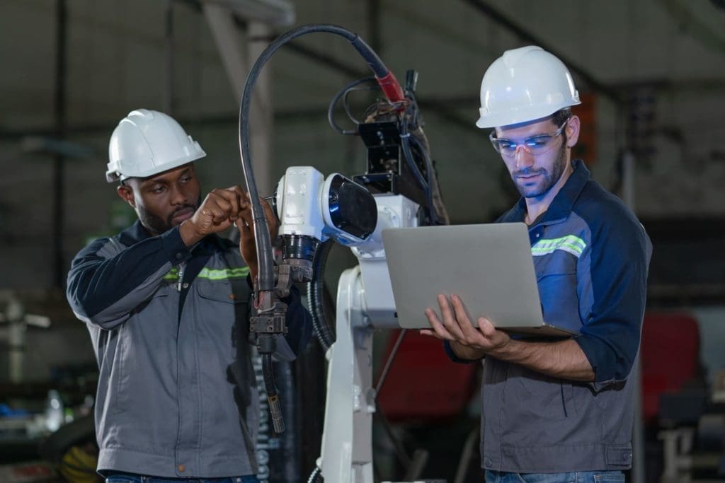 Deux techniciens de maintenance industrielle réparant une machine dans l'usine.